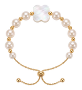 Bracciale di perle bianche con un fiore in madreperla a quattro petali, indossato al polso
