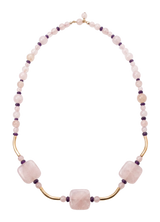 Collana di grani di quarzo rosa con due pietre sfaccettate e curve d'argento, indossata sul petto
