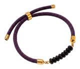 Tre bracciali in cordoncino di seta viola e verde, con terminali dorati e una pietra naturale al centro