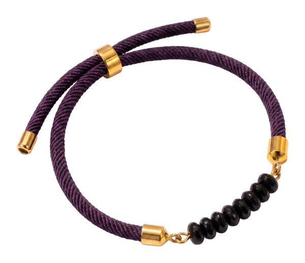 Tre bracciali in cordoncino di seta viola e verde, con terminali dorati e una pietra naturale al centro