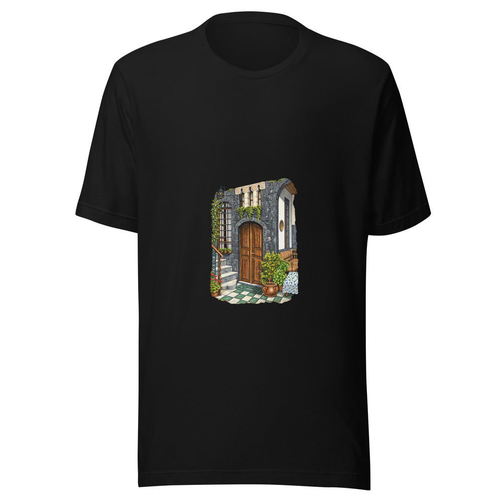 Maglietta unisex nera vista di fronte. Una porta in legno occupa il centro della parete in pietra, tra finestre alte, scalini e vasi verdi. Mockup del capo completo.