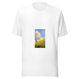 Maglietta unisex bianca vista di fronte. Una piccola figura porta la bandiera palestinese su un pendio fiorito, sotto grandi nuvole luminose. Mockup del capo completo.