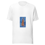 Maglietta unisex bianca vista di fronte. Una figura volta il viso verso chi guarda; la veste policroma risalta fra tessuti, cuscini e lanterne blu. Mockup del capo completo.